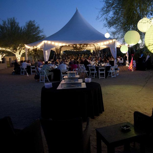 Outdoor wedding under a hexagon rental tent with globe and twinkle lighting to add ambience to the event.